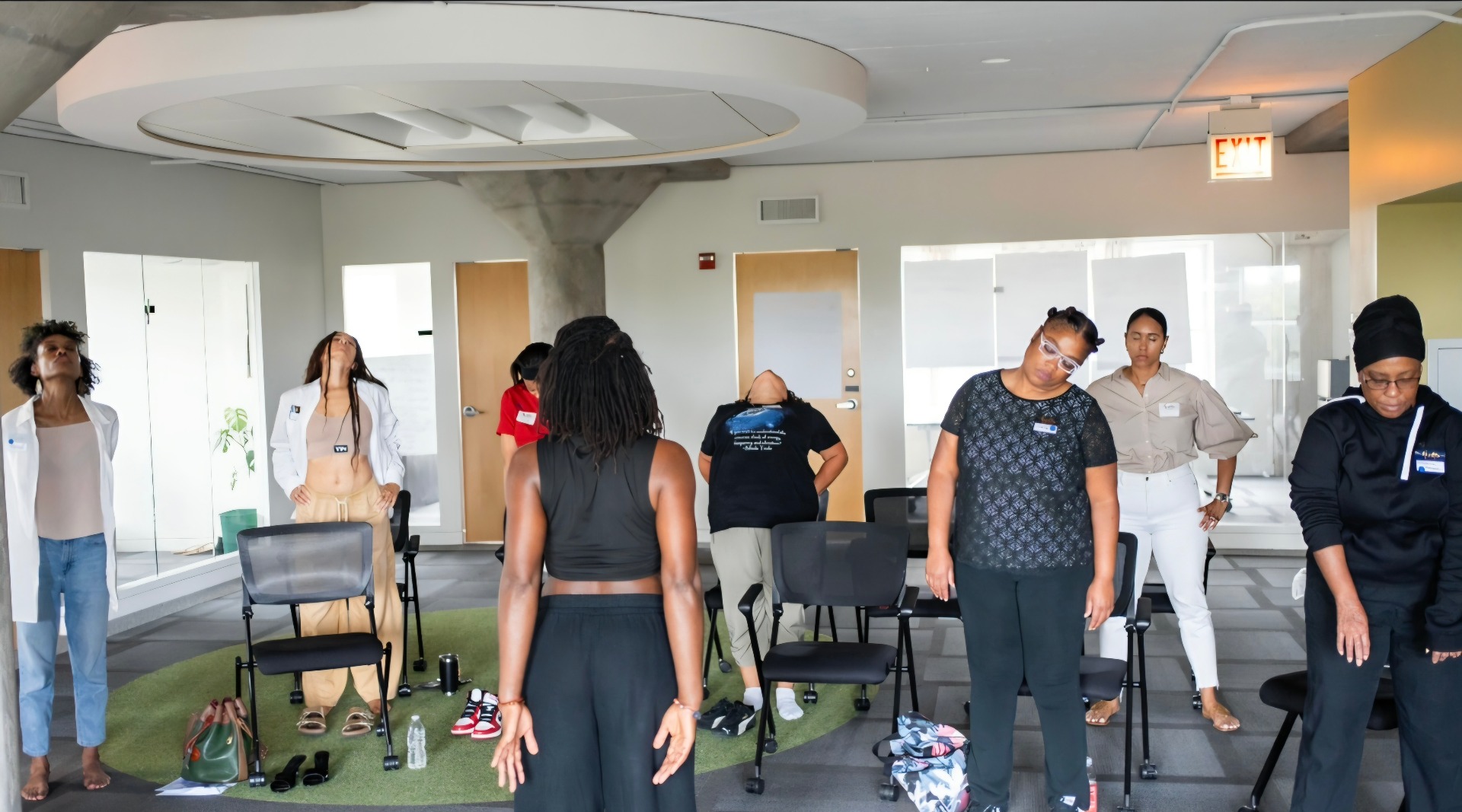 A group of professionals standing in a guided grounding exercise during a workplace wellness session